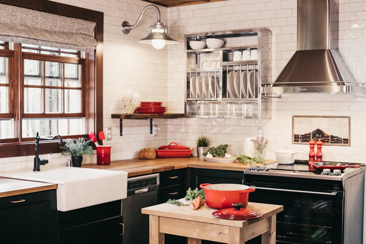 Kitchen with dark cabinets, butcher block countertops, and farmhouse sink showing a classic L-shape layout (Photo: Becca Tapert / Unsplash)