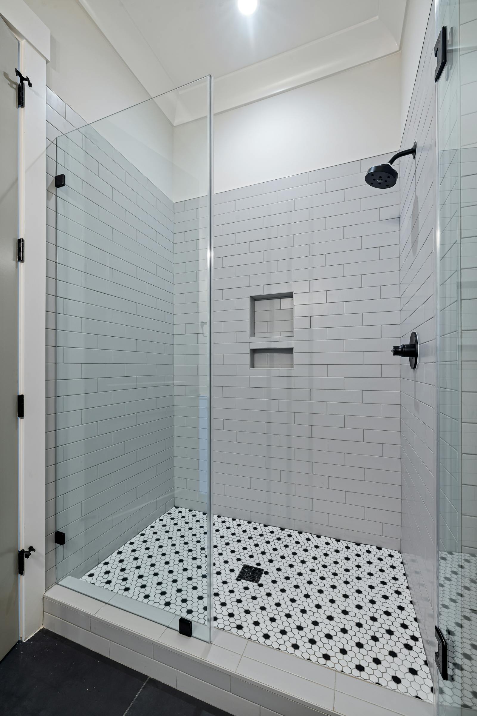 Frameless glass walk-in shower with white subway tile and a built-in niche