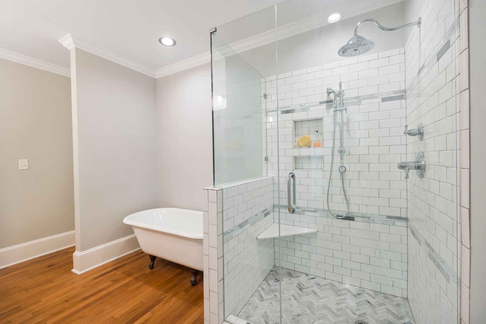 A walk-in shower behind a clean wall of frameless glass — the frameless look showcases the tile instead of hiding it behind a metal frame
