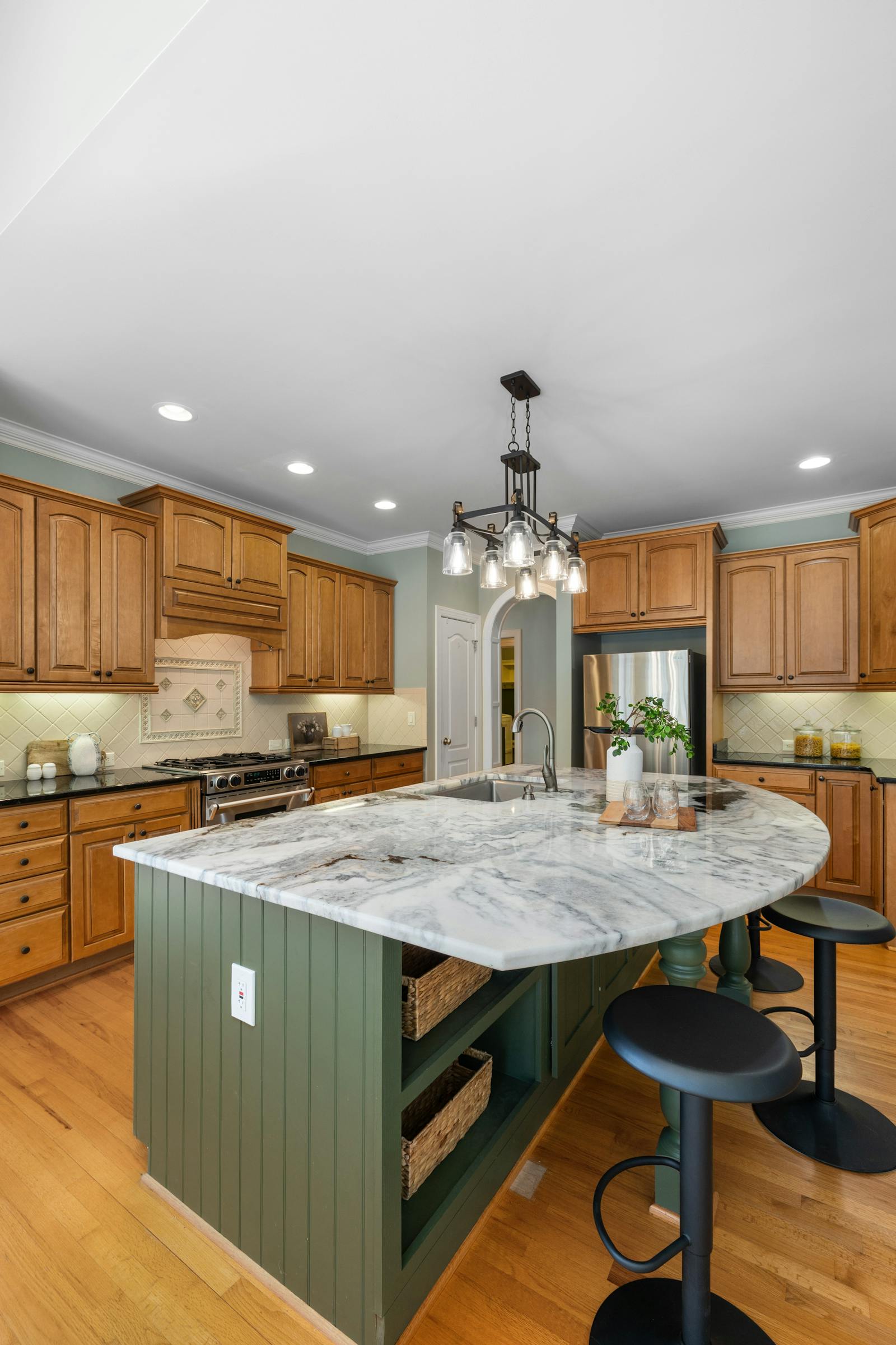 A kitchen island topped with dramatically veined marble — book-matching a bold natural stone like this across the corner is what makes a waterfall edge stand out