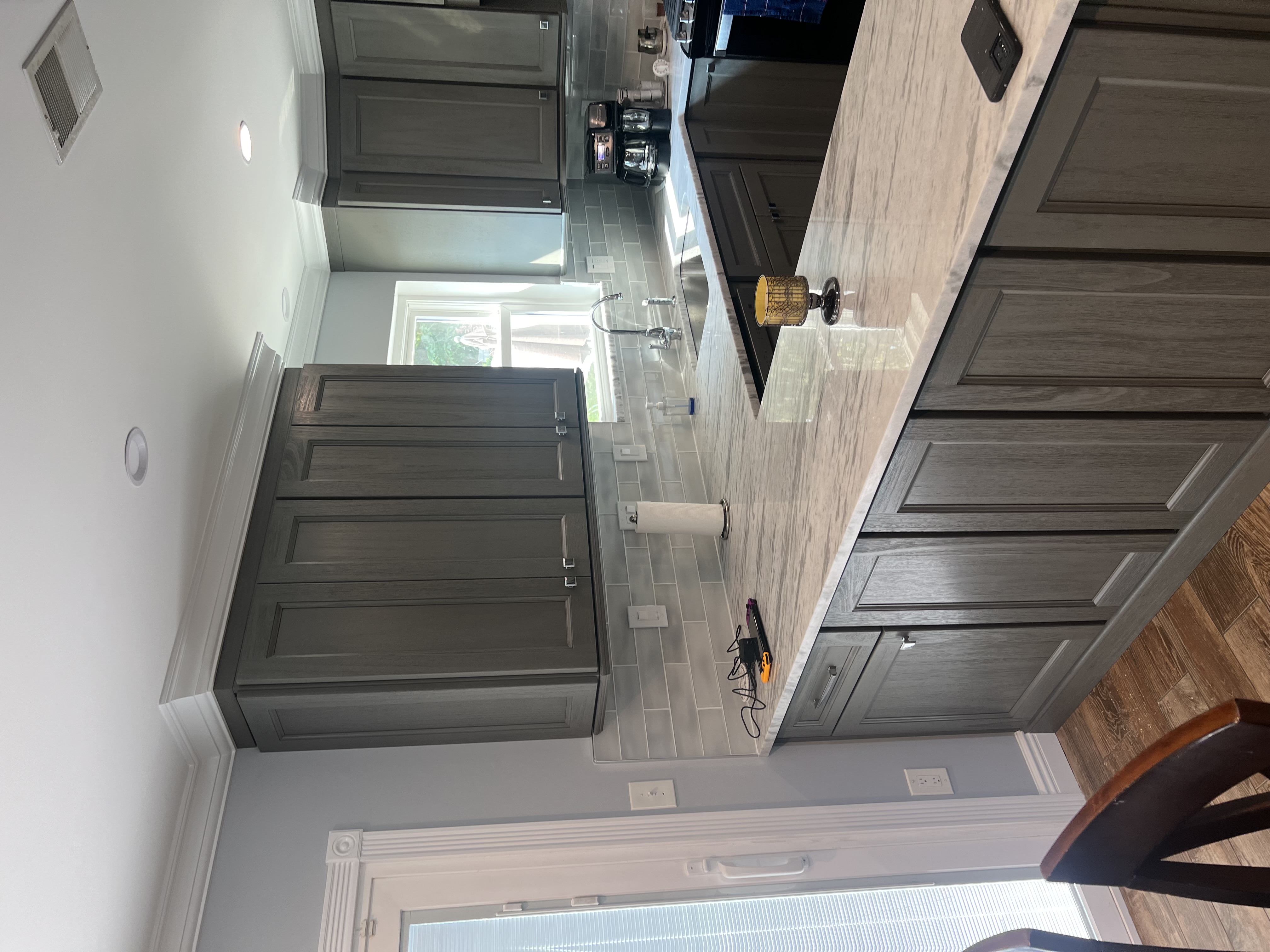 Custom gray kitchen cabinetry detail with crown molding, continuous countertop run, and tile backsplash
