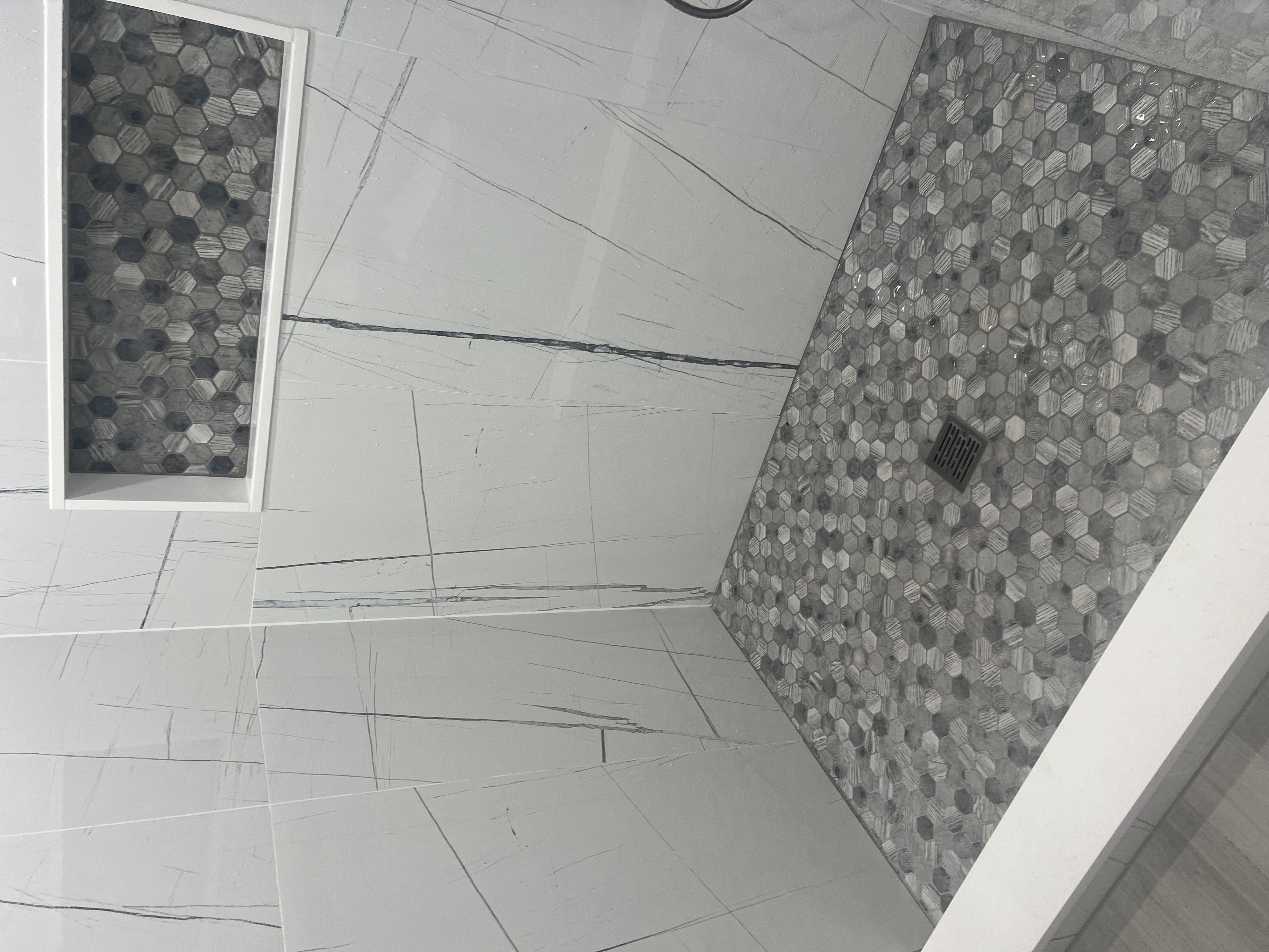 Walk-in shower floor with linear drain, low curb, large-format wall tile, and recessed niche